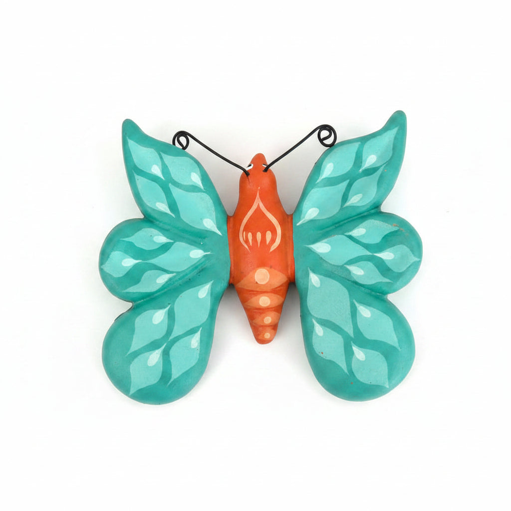 Decorative butterfly with teal wings and orange body on a white surface